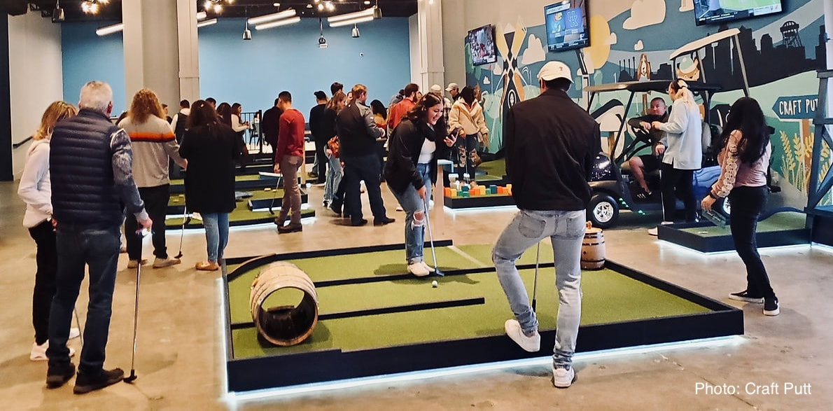 Photo of adults playing mini golf indoors.